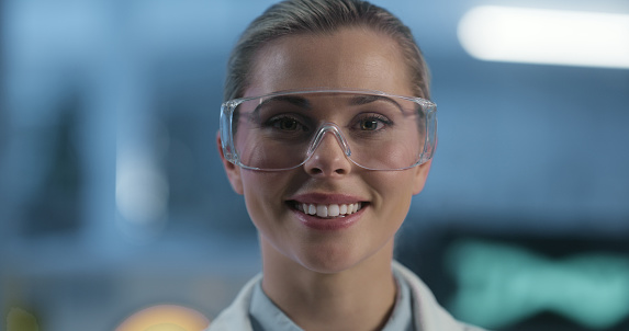 Portrait, science and woman in goggles as a doctor in a laboratory for research or innovation in medicine. Face, smile and safety with a happy young scientist in a lab for breakthrough or development