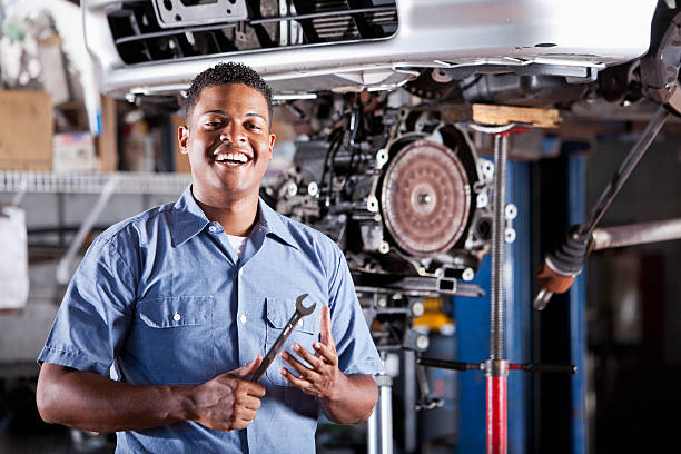 Auto mechanic fixing car transmission African American auto mechanic (30s) repairing a car, working on the transmission. car mechanic top view stock pictures, royalty-free photos & images