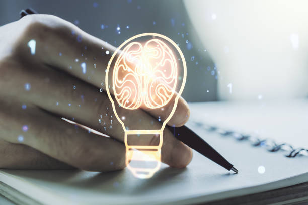istock Double exposure of creative light bulb hologram with human brain and with man hand writing in notebook on background, idea and brainstorming concept 1751695662
