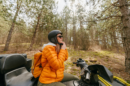 Photo of a young woman putting a helmet on while riding a quad bike during an autumn adventure