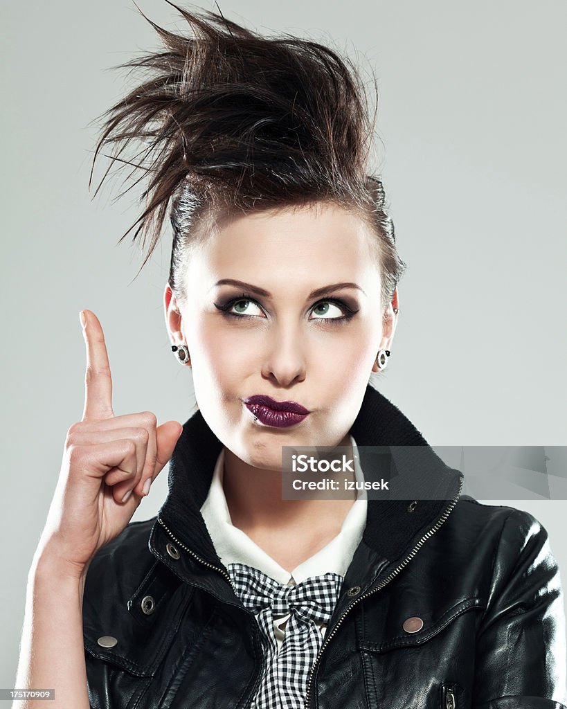 Punk Girl, portrait Portrait of displeased young woman in punk style holding her index finger up and laughing up. Studio shot. Displeased Stock Photo