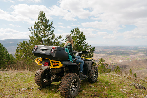 Photo of a young woman sitting on a quad bike and enjoying the view