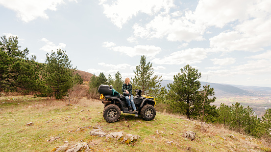 Photo of a young woman sitting on a quad bike and enjoying the view