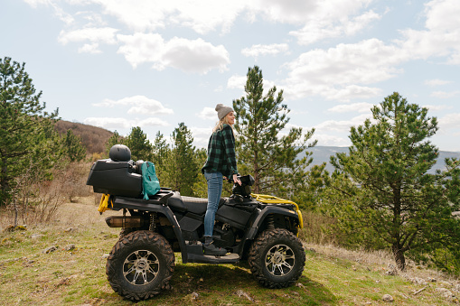 Photo of a young woman sitting on a quad bike and enjoying the view