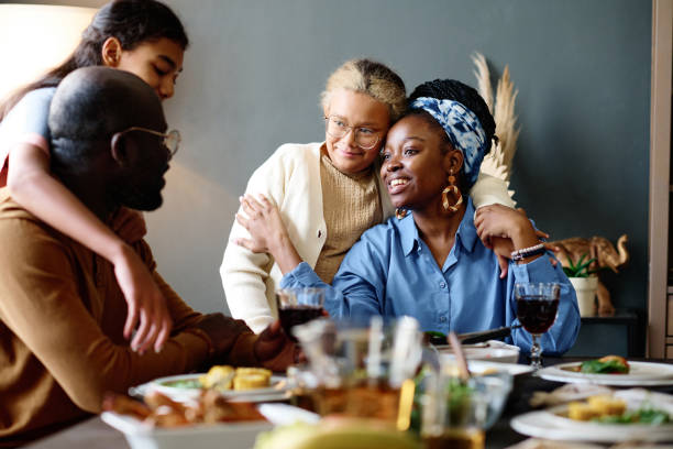 istock Two affectionate daughters embracing their father and mother sitting by table 1751720260