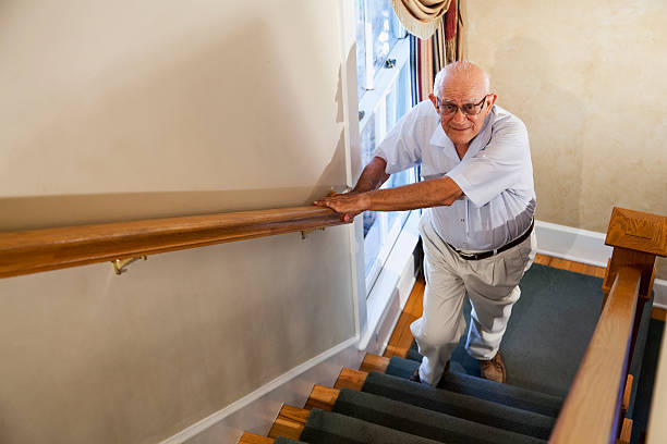 uomo anziano fare le scale - stair rail foto e immagini stock