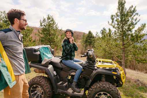 Photo of a smiling couple riding a quad bike on their autumn adventure