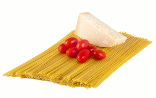 Uncooked spaghetti with small tomatoes and Parmesan isolated on white