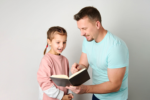 Young father and daughter reading book close-up. Young dad and his little daughter reading book on white background with copy space