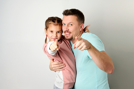 Happy young father hugging his daughter. Playful dad with his child, white background