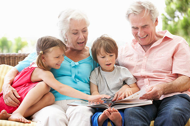 dziadkowie i wnuki czyta książkę na ogród siedzenia - grandmother reading child grandson zdjęcia i obrazy z banku zdjęć