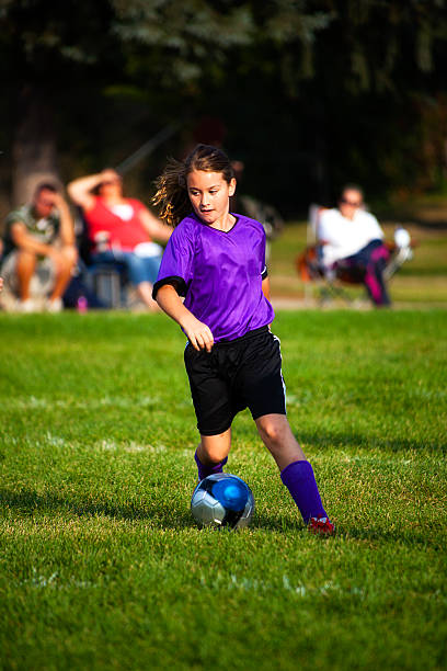 kind fußballspieler dribblings ball im golden sunight und copyspace - soccer action child purple stock-fotos und bilder