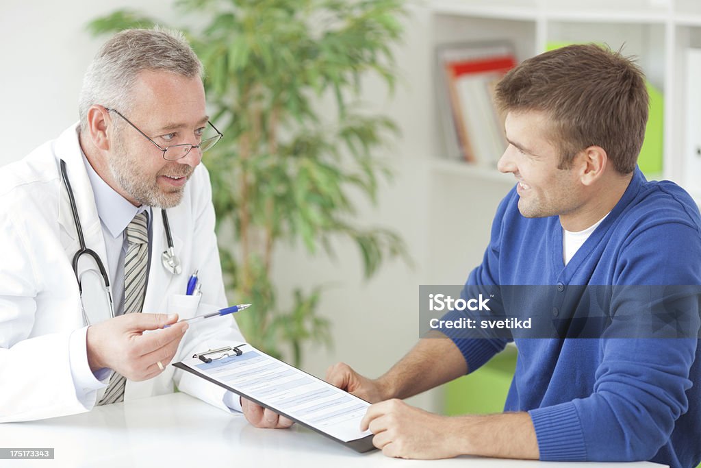 Man at doctor's office. Doctor showing form to male patient at his office.See more LIFESTYLE and MEDICAL images with this COUPLE and DOCTOR or CONSULTANT. Click on image below for lightbox. 30-39 Years Stock Photo