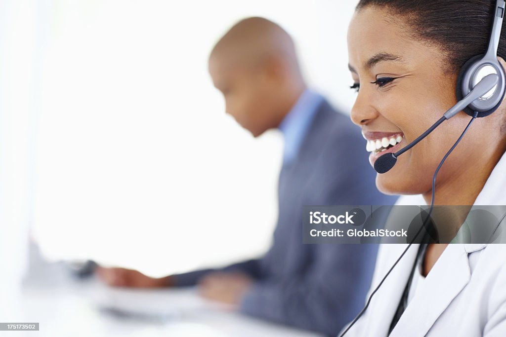 Hard at work in the callcentre Cropped image of a businesswoman talking on her headset with a blurred colleague in the background Adult Stock Photo