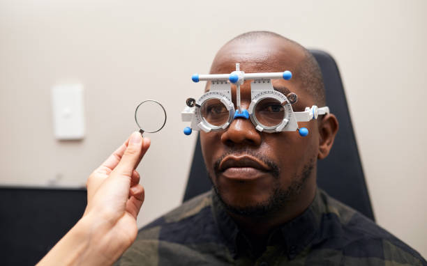 istock Optometry, eye test and patient with trial lens for vision in an optical clinic or store. Optometrist, equipment and hands of optician with black man for prescription lenses for eyesight  in a shop 1751735259