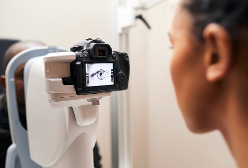 Woman, optometrist and refractometer for eye exam, vision and healthcare in clinic. Technology, ophthalmologist and doctor test eyesight, check and monitor on lens or machine in medical consultation