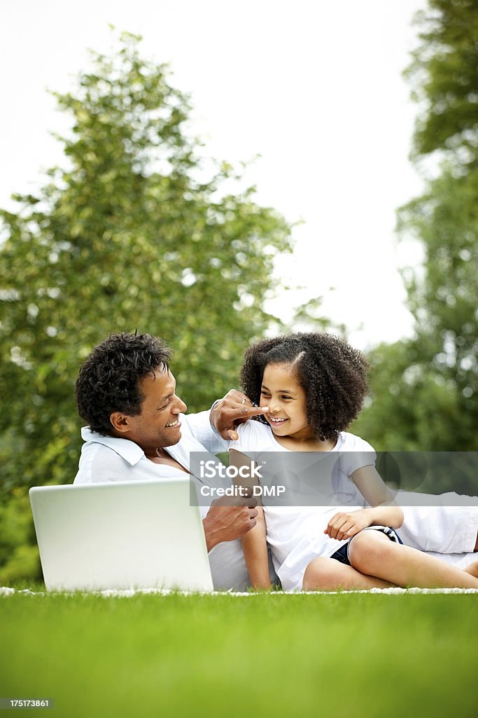 Happy father and daughter with a laptop in park Happy father and daughter lying on ground in park with a laptop Adult Stock Photo