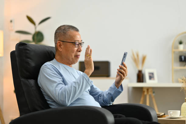 istock Happy elderly man waving hand, speaking on video call talking to family while resting on armchair at home 1751743067