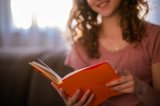 Close-up of a teenage girl reading a book at home