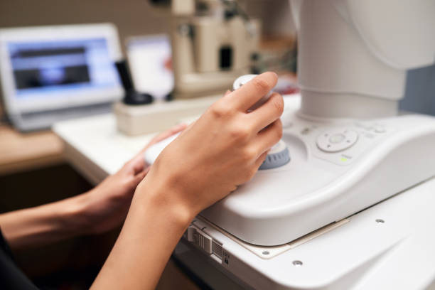 Closeup hand, optometry machine and a test for glaucoma, eye care or vision check. Ophthalmologist, professional and fingers or person with equipment for a healthcare, lens or eyes test at a clinic