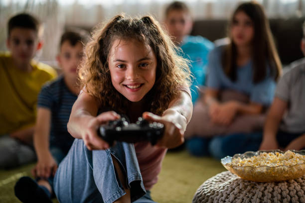 istock Girl playing video game on console while her friends looking at background 1751752739