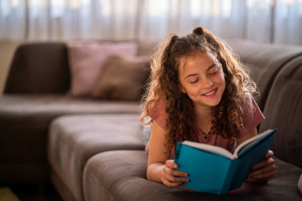istock Happy girl lying on sofa and reading a book 1751757891