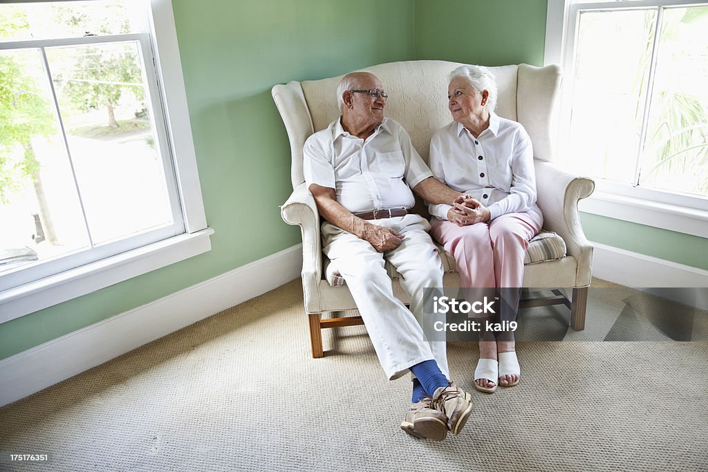 Anziani coppia seduta insieme sul divano a due posti - Foto stock royalty-free di 70-79 anni
