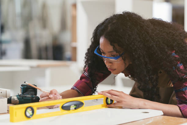 istock Female carpenter using water level meter or spirit level tool design work in wood workshop. Female joiner working at furniture workshop 1751765268
