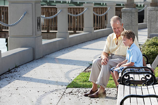 Senior man with grandson on park bench Grandfather (70s) with grandson (6 years), sitting outdoors on park bench. Sc0560 stock pictures, royalty-free photos & images