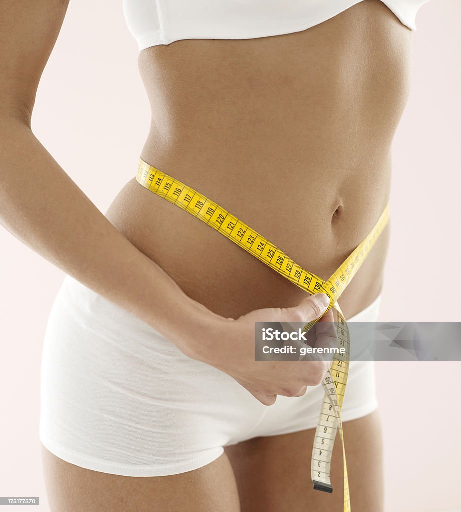 Woman measuring hips with tape measure. Close up of woman measuring hips with tape measure. 20-29 Years Stock Photo