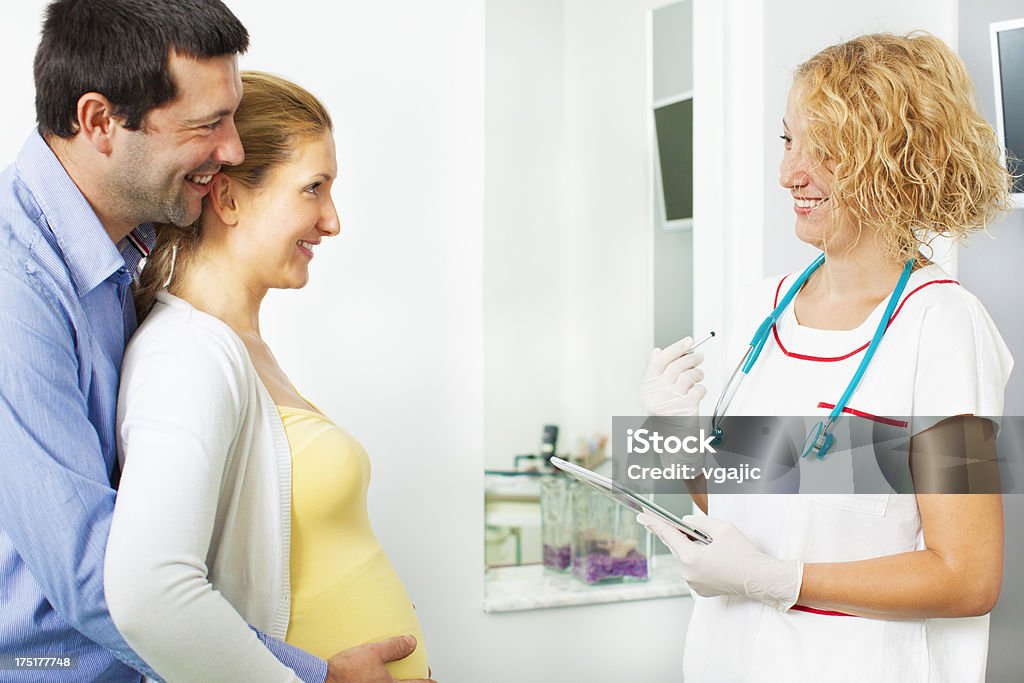 Joven pareja embarazada visita médico. - Foto de stock de Consultorio médico libre de derechos