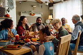 Happy multiracial extended family celebrating Thanksgiving at dining table.
