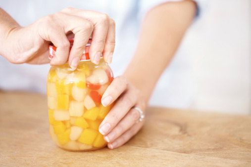 Cropped image of a woman tightening a jar in the kitchen