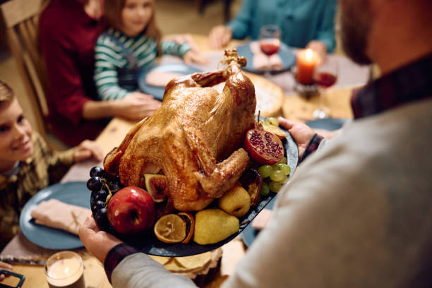 istock Close up of father bringing Thanksgiving turkey at dining table. 1751789469