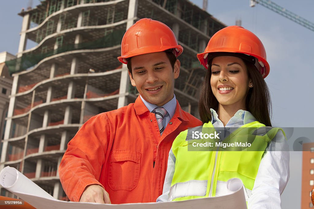 Building Contractor Building Contractor Discuss Blueprints at a Construction Site Agreement Stock Photo