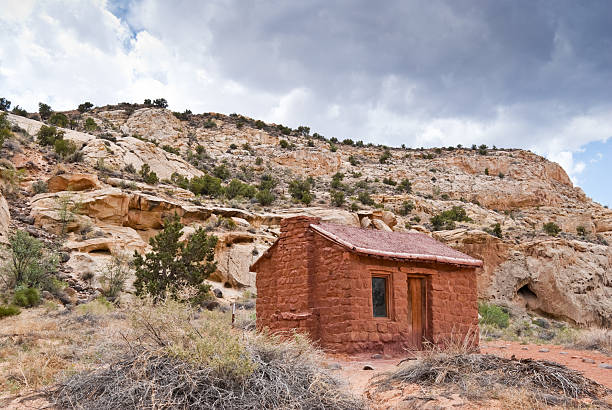 Historic Behunin Cabin Elijah Cutler Behunin was a Mormon pioneer. He and his family lived in a one room sandstone cabin between 1883-84. The Behunins lived there for only a year, leaving for Fruita, Utah after a flood threatened the house and its fields. The cabin is preserved in what is now Capitol Reef National Park, Utah, USA. jeff goulden mojave desert stock pictures, royalty-free photos & images