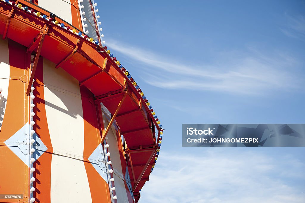 Helter Skelter - Fairground Ride Part of an orange and white coloured Helter Skelter fairground ride against a blue sky. Plenty of space to the right of frame for type. Amusement Park Stock Photo