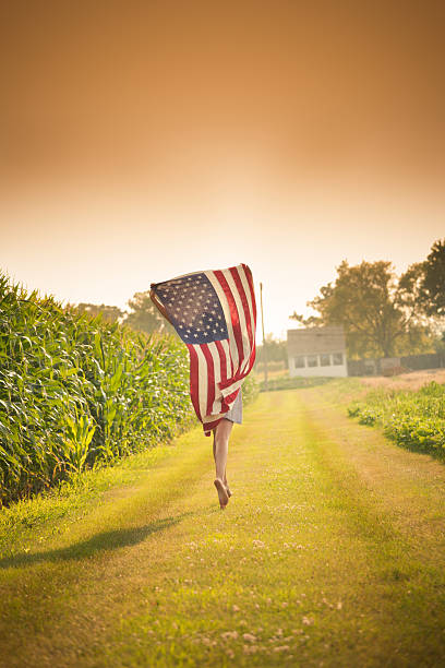 ファームの女の子を横切るフィールド、u .s .  旗 - footpath single lane road road farm ストックフォトと画像