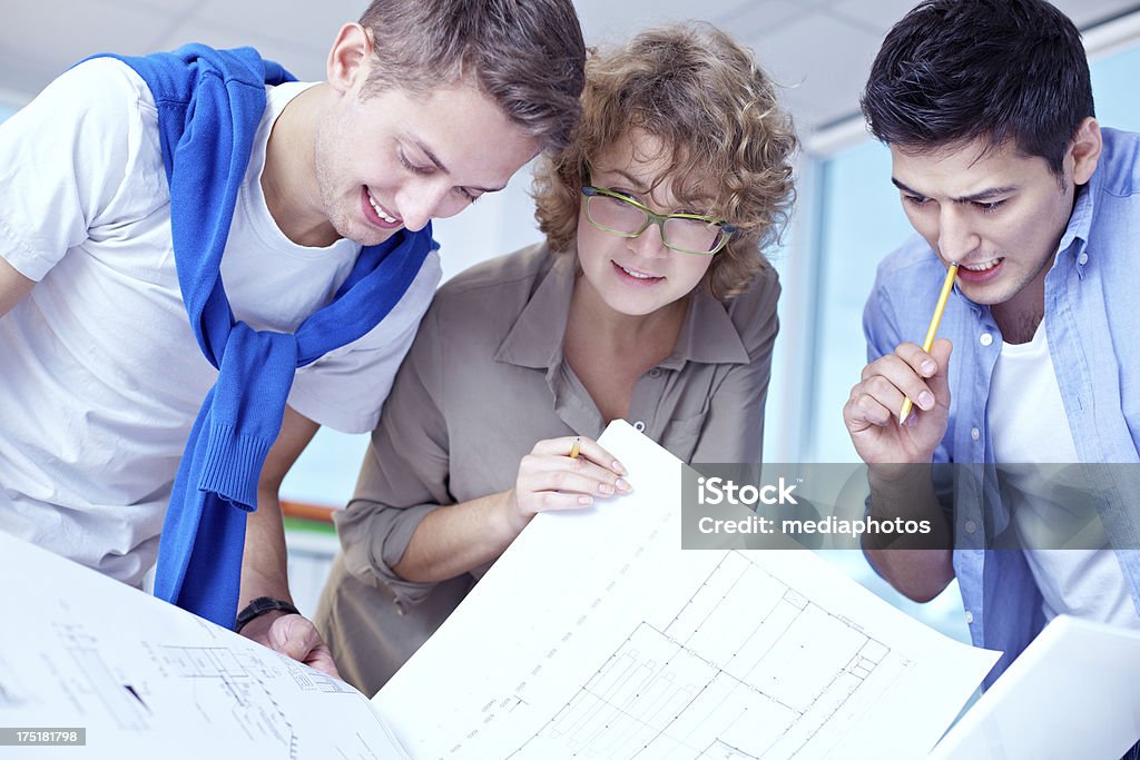 Designers with blueprints Team of designers planning new architectural project together 20-24 Years Stock Photo