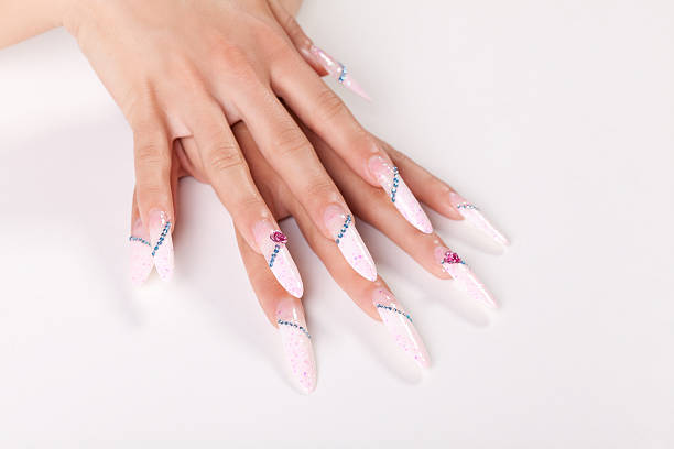 Acrylic fingernail with pink nail polish decorated with blue zircons.