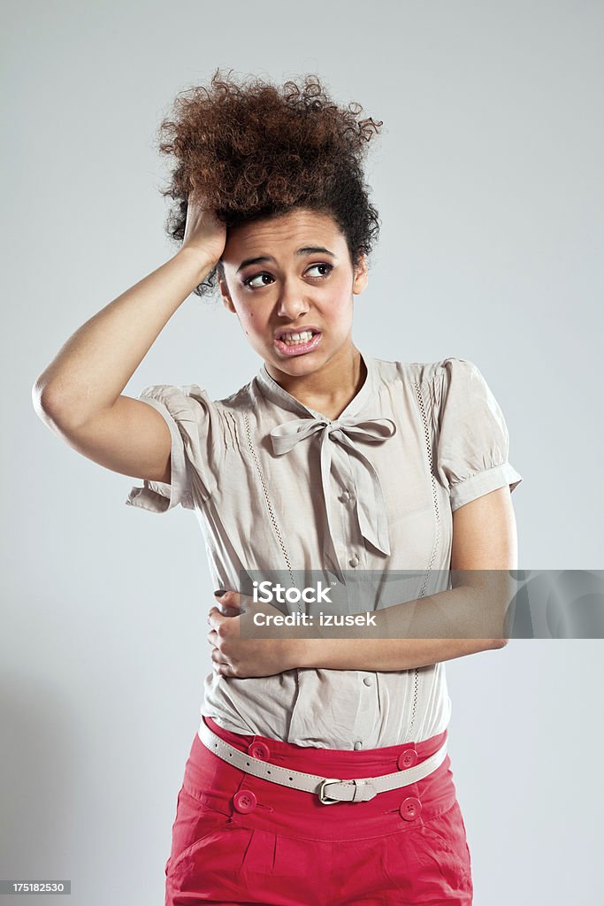 Problem Portrait of teenaged afro girl looking away with hand in hair. Studio shot, grey background. Assistance Stock Photo