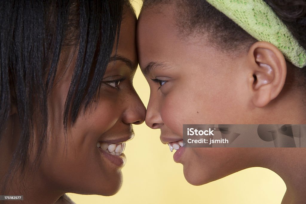 Daughter and mother face each other "African american mom and daughter exemplify genuine love for each other. Real mom and daughter. I think it matters, and makes the shot. i see this as spread with fold somewhere, might be nice black and white as faded background for inside brochure or folder or book cover wrap. single parent ads, perhaps." Adolescence Stock Photo
