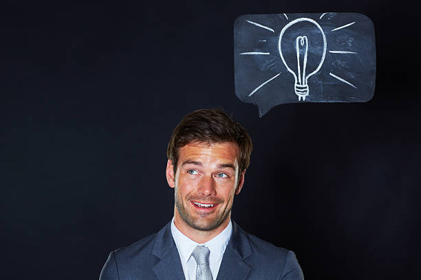I think I've got it A handsome businessman looking excited with a lightbulb drawn on the chalkboard above him man with a light bulb over his head stock pictures, royalty-free photos & images