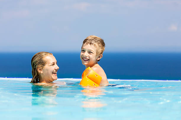 madre y niños nadar en la piscina de borde infinito - sports venue luxury love enjoyment fotografías e imágenes de stock