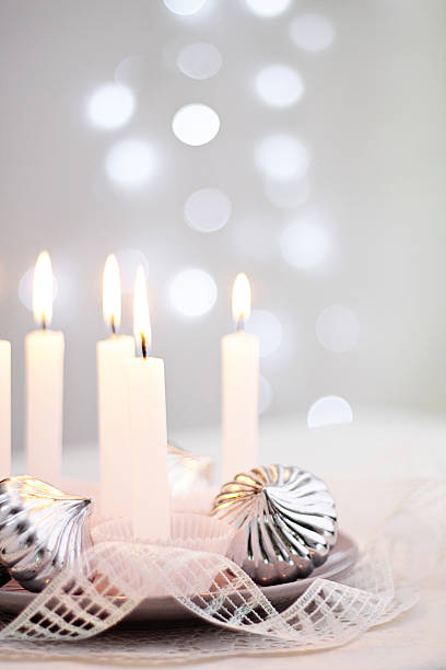 Centrepiece with silver Christmas ornaments, candles and Christmas lights background stock photo