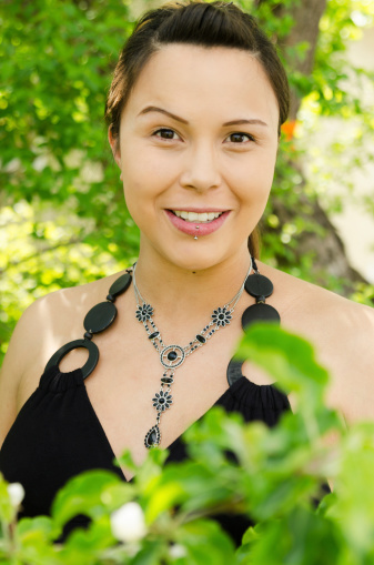 Vertical outdoor garden shot of young woman in black with single raised eyebrow.