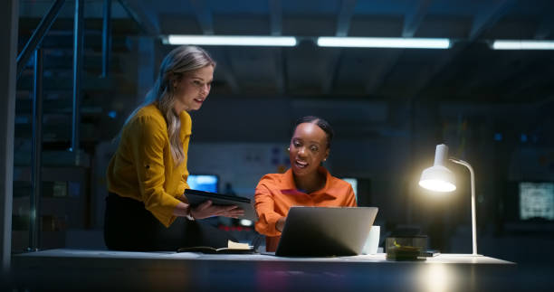 istock Tech, night and coaching, women in office together with tablet and laptop for advice, coaching and planning. overtime, tech startup and woman with manager at desk in research, review or brainstorming 1751843408