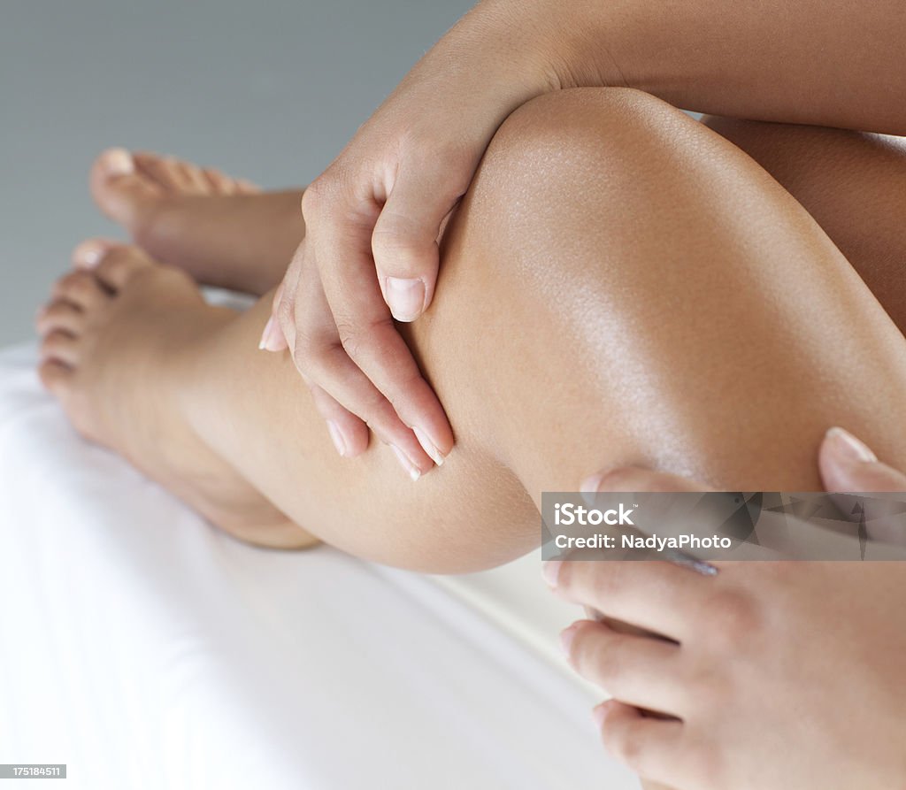 Massaging on lotion a part of a skin care routine  Close up of a perfect female legs. Woman applying moisturizer.  Women Stock Photo