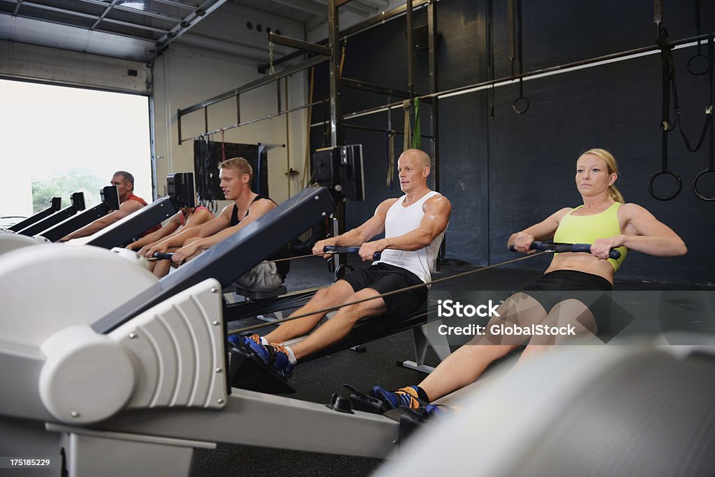 Timing and form are everything to a rower A group of people on the rowing machines at gym Rowing Machine Stock Photo