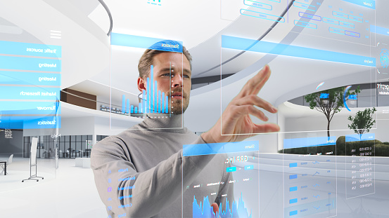 Handsome Man Standing in Futuristic Virtual Space, Interacting with an Augmented Reality Hologram with Business Data, Financial Reports, Stock Market Statistics, Infographics and Charts